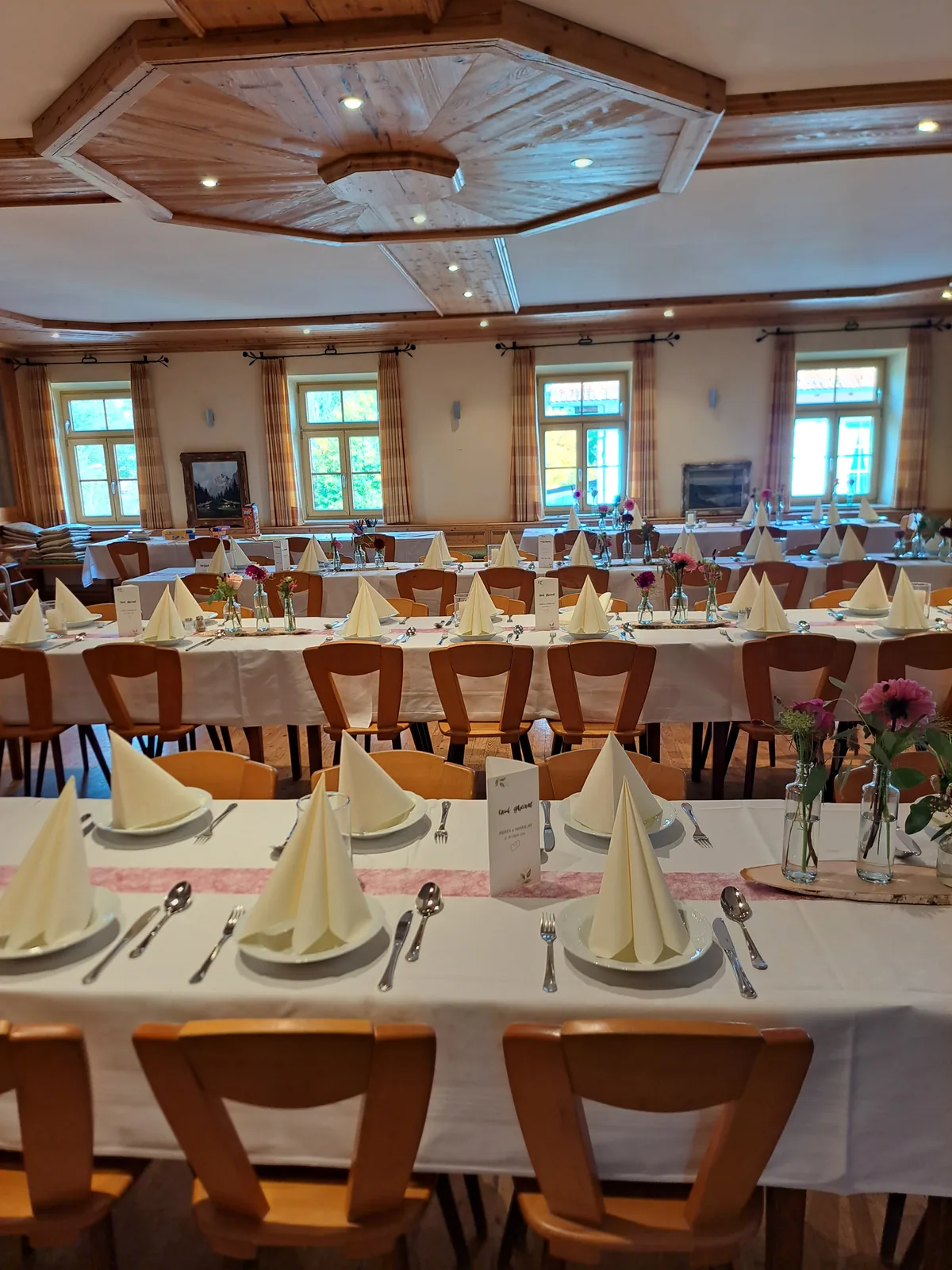Gastraum mit kassettierter Holzdecke und festlich gedeckten Tischen